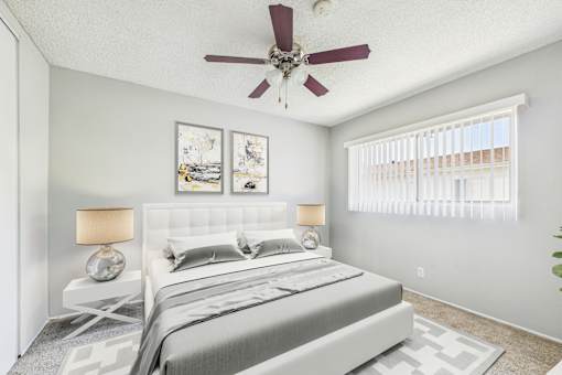 A bedroom with a bed, two lamps, and pictures on the wall.