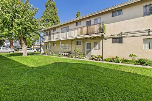 A building with a balcony and a green lawn in front.