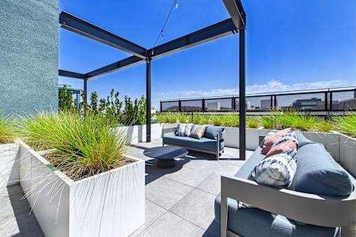 A person is sitting on a chair under a pergola with a planter box in front of them.