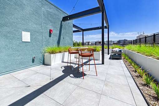 A patio with a table and chairs is in front of a green wall.