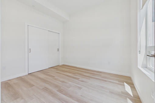 A room with a white door and wooden flooring.