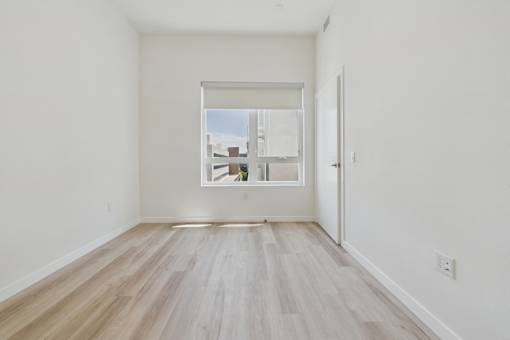 A room with a window and wooden flooring.