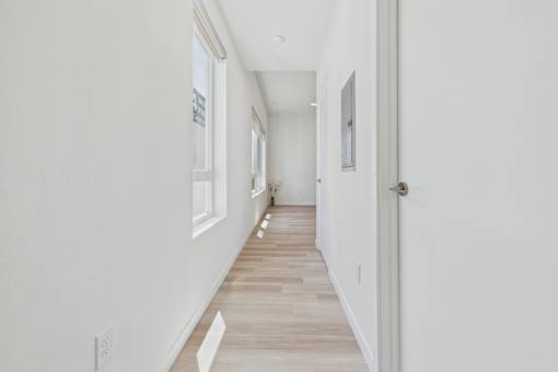 A long hallway with white walls and wood flooring.