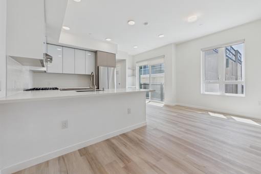 A kitchen with white cabinets and a wooden floor.