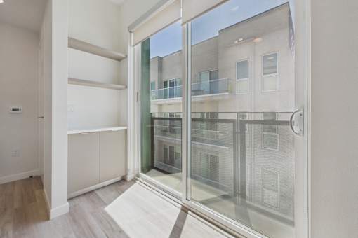 A room with a sliding glass door leading to a balcony.