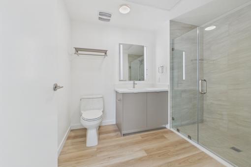 A white toilet sits in a bathroom with a walk-in shower.