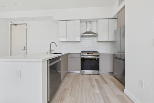 A modern kitchen with stainless steel appliances and wooden flooring.