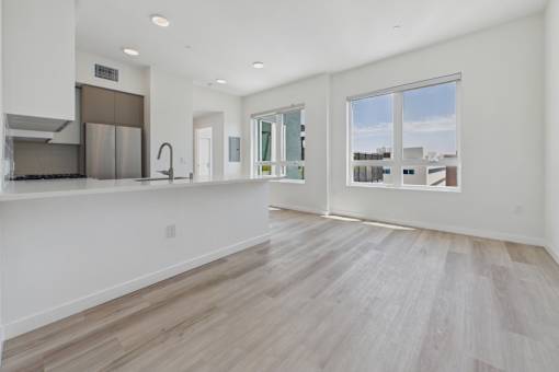 A spacious kitchen with a refrigerator, sink, and a window overlooking the city.