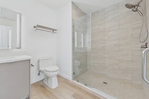 A white toilet sits in a bathroom with a walk-in shower.