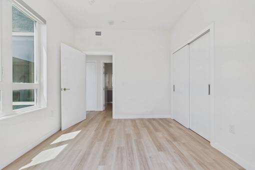 A long white hallway with wood flooring and white walls.