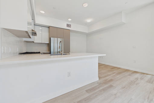 A kitchen with white countertops and a wooden floor.
