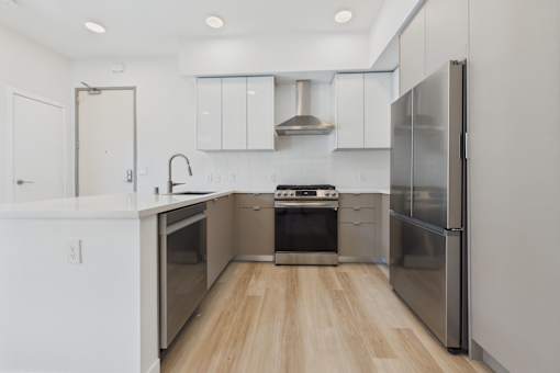 A modern kitchen with stainless steel appliances and wooden flooring.