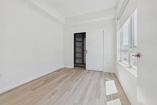 A room with a white door and a wooden floor.