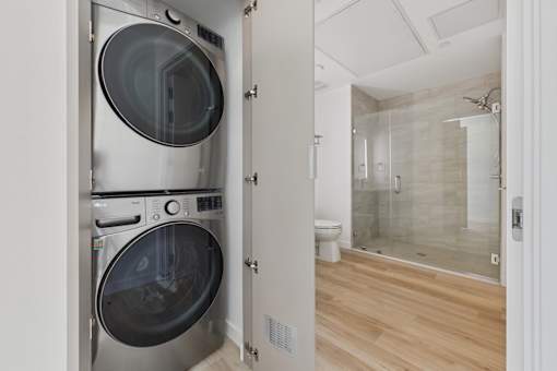 A modern laundry room with a washer and dryer built into a wall unit.
