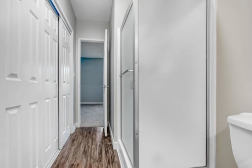a bathroom with white cabinets and a door to a closet