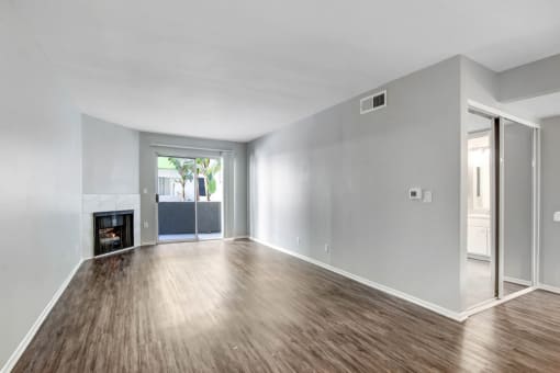 an empty living room with a fireplace and wooden floors