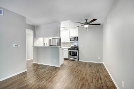 an empty living room and kitchen with a ceiling fan