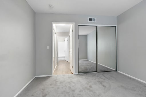 an empty bedroom with mirrored closet doors and a carpeted floor