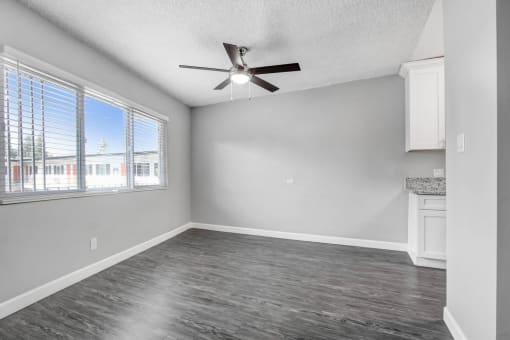 an empty living room with a ceiling fan and a window