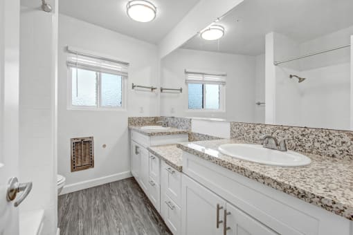 a bathroom with white cabinets and granite counter tops