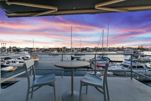 a view of a marina with boats in the water and a patio with chairs