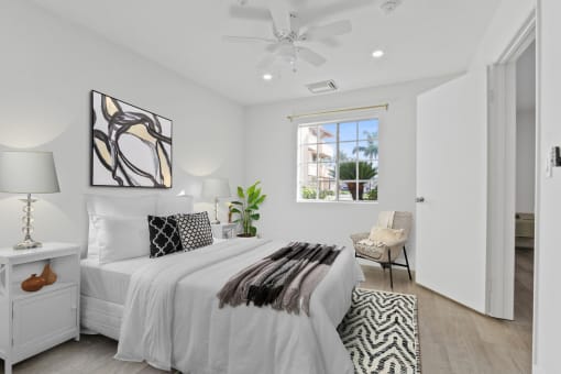 a white bedroom with a bed and a ceiling fan