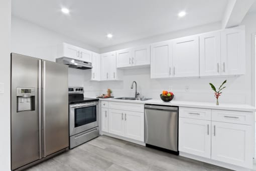 a white kitchen with stainless steel appliances and white cabinets