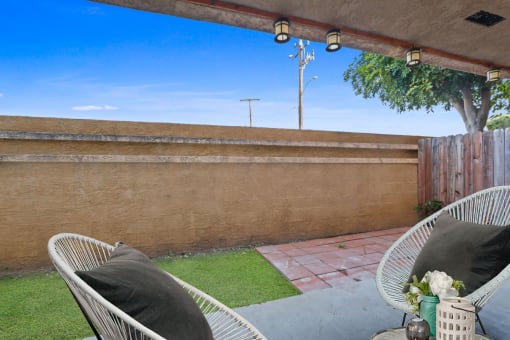 a backyard patio with two chairs and a privacy fence