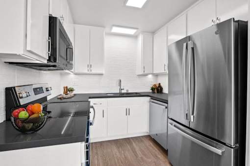 A modern kitchen with a black countertop and stainless steel appliances.