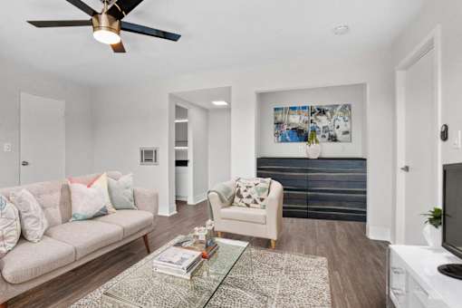 A living room with a couch, a chair, a coffee table, and a ceiling fan.