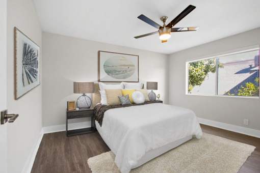 A bedroom with a white bed and a ceiling fan.