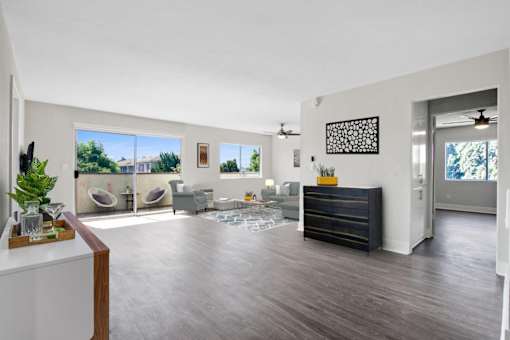 A living room with a white wall and a black dresser.