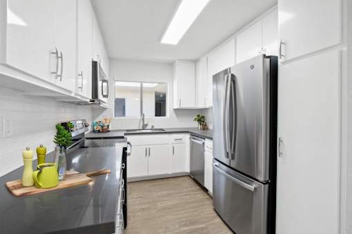 A modern kitchen with a stainless steel refrigerator and white cabinets.