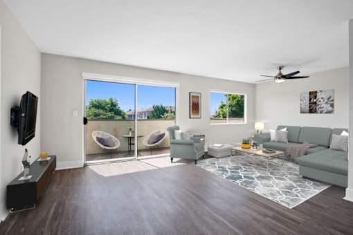 A living room with a grey couch, a television, and a fan.