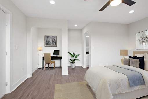 A bedroom with a large bed and a desk with a chair.