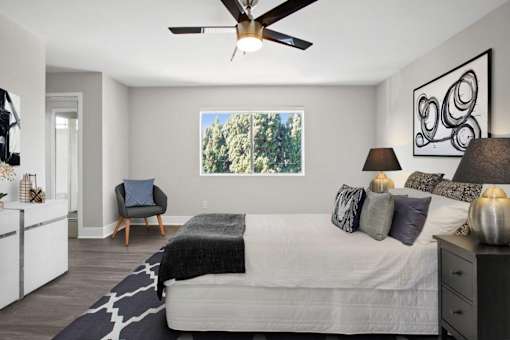 A bedroom with a bed, a chair, and a ceiling fan.