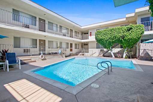 A pool in a courtyard surrounded by a white building.