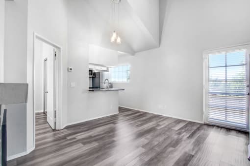 an empty living room with a kitchen and a window