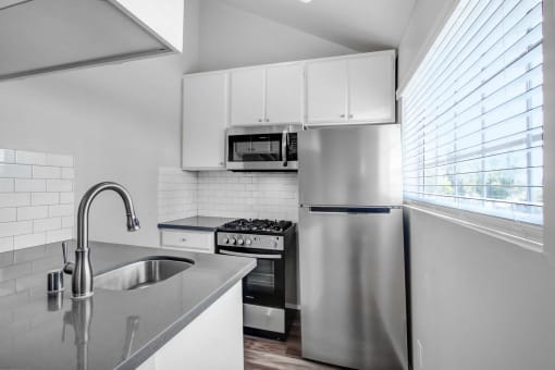 a kitchen with a sink and a stainless steel refrigerator
