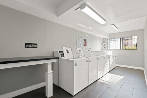 a laundry room with four washers and a row of washing machines