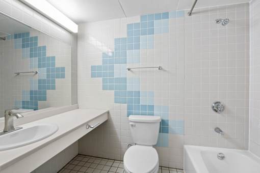 A white toilet sits in a bathroom with blue tiles.