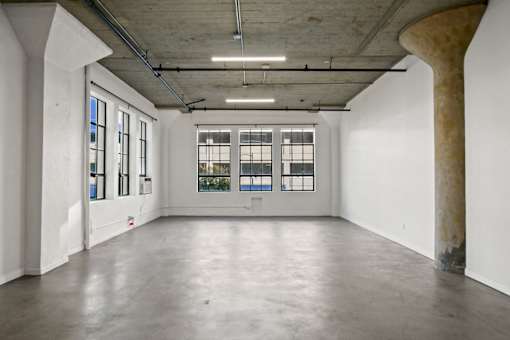 A large empty room with a concrete floor and a large column on the right side.