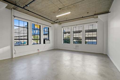 A large empty room with three windows and a concrete floor.