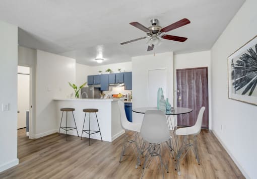 a dining area with a table and chairs and a kitchen in the background