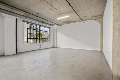 A large empty room with a window and a door.