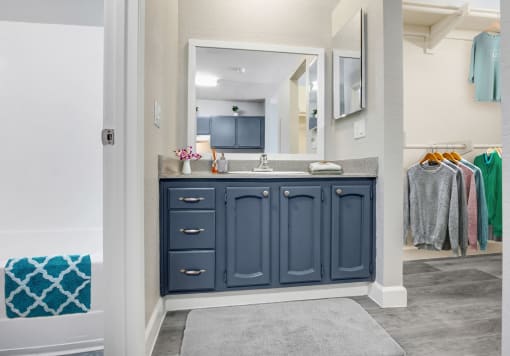 a bathroom with blue cabinets and a gray rug