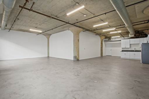 A large empty room with a concrete floor and white walls.