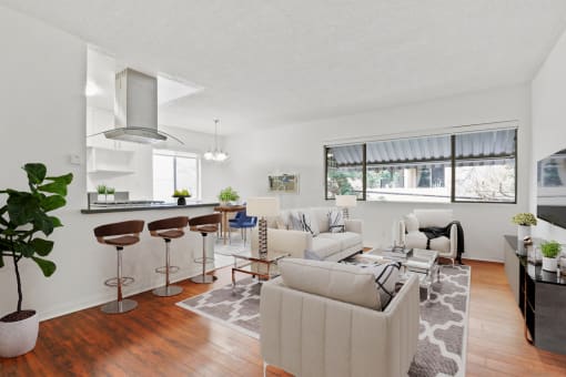 the living room and kitchen of an apartment with white couches and stools
