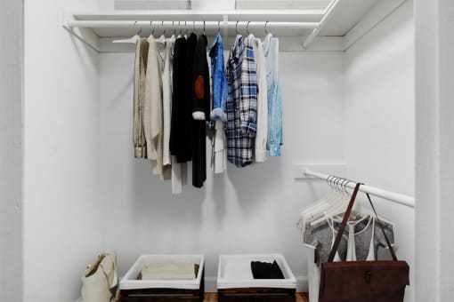 a closet with clothes hanging on a rack and two boxes on the floor