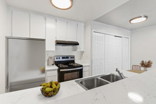 a white kitchen with stainless steel appliances and a counter top